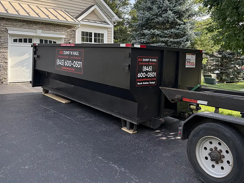 Black 20-yard container placed on a residential driveway in Poughkeepsie, NY — 845 Dump 'N Haul