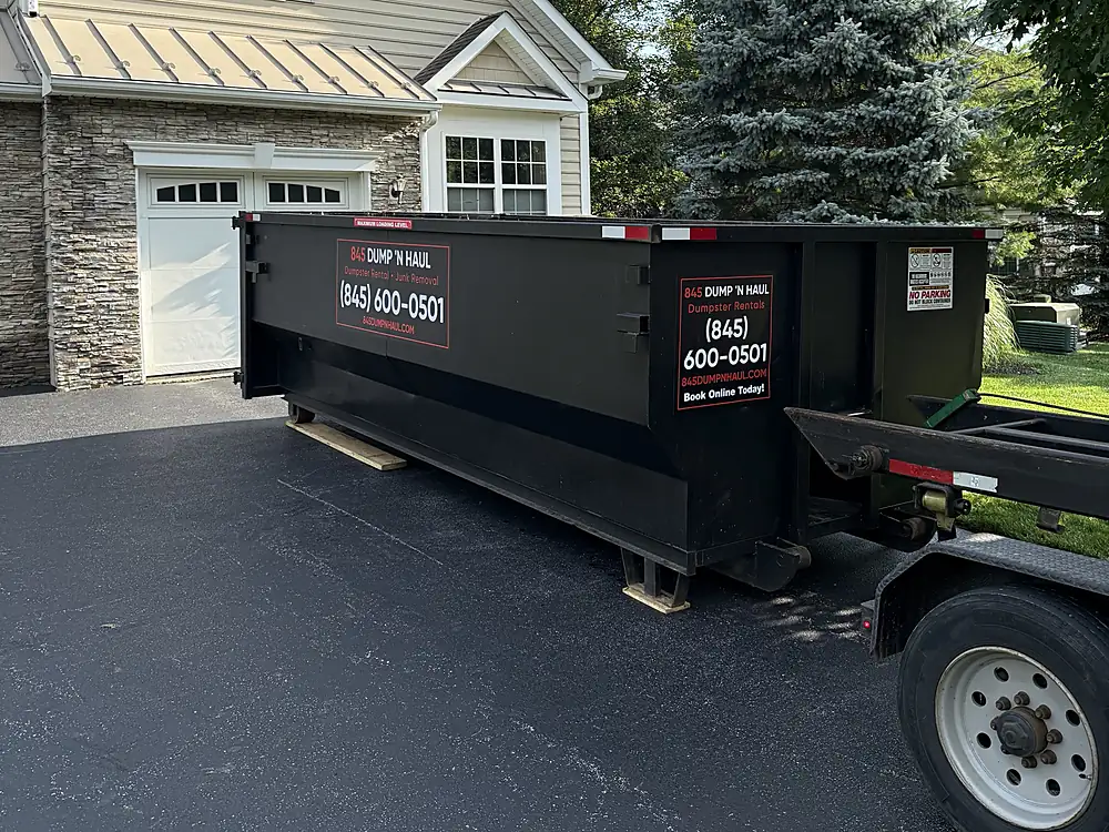 Black 20-yard roll-off dumpster on a colonial home driveway — 845 Dump 'N Haul, Dutchess County NY