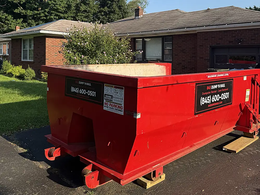 Red dumpster on the driveway of a brick ranch home in Poughkeepsie, NY — 845 Dump 'N Haul