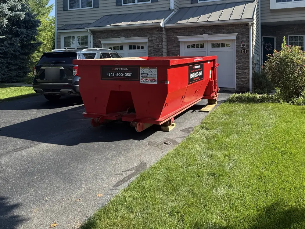 Red roll-off dumpster on a townhouse driveway — 845 Dump 'N Haul, Dutchess County NY